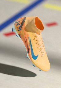 Scarpini da calcio Nike di un vivace arancione con accenti blu, design elegante, tallone alto, upper testurizzato e suola a contrasto per una migliore aderenza.