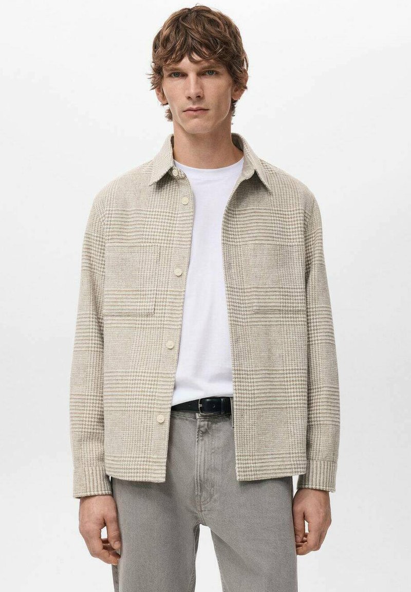 Camisa de botones a cuadros beige hecha de tela texturizada, con dos bolsillos delanteros, cuello abotonado y botones de color crema.