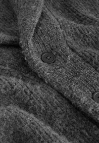 Gray knitted cardigan featuring a textured pattern, large black buttons, and a soft, fuzzy wool-like material.