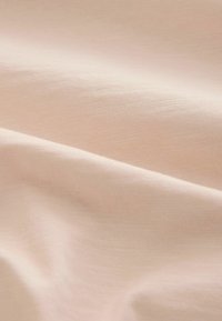 Pehme beež kangas peene kootud tekstuuriga, mis näitab õrnu voltisid ja kergeid varje.