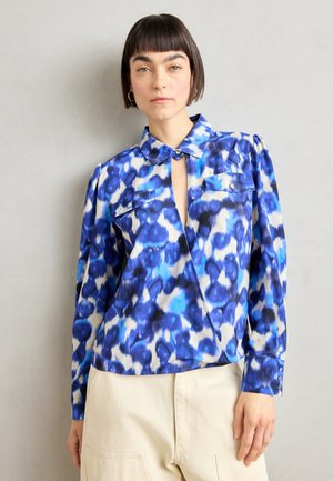 Blå mønstret skjorte med krage, knappestolpe foran og to brystlommer. Stoffet har en glatt tekstur og et livlig design.