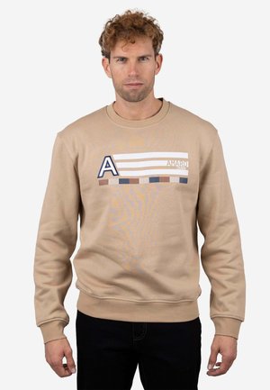 Sudadera beige con cuello redondo y puños acanalados. En el frente presenta un diseño gráfico con rayas azules y blancas y un destacado logotipo en forma de 'A'.