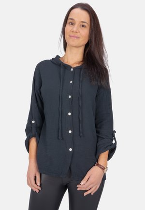 Schwarzes, leichtes, kapuzen Shirt aus strukturiertem Stoff, mit Knopfleiste und aufgerollten Ärmeln. Mit Kordelzügen und weißen Knöpfen ausgestattet.