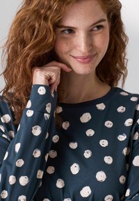 Navy long-sleeve shirt with white circular patterns, featuring a round neckline and soft, textured fabric.