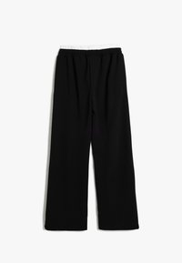 Zwarte, wijde broek met een elastische tailleband en een witte binnenvoering aan de bovenkant. Gladde stof zonder extra patronen of versieringen.