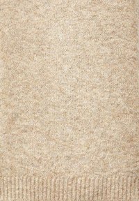 Beżowa dzianinowa tkanina swetra o miękkiej fakturze, z delikatnym wzorem i ściągaczem na dole dla struktury.