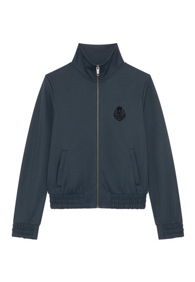 Marineblauwe jas met hoge kraag, volledige rits, twee zijzakken, elastische manchetten en een gestructureerd zwart wapen op de borst.