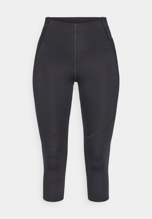 Zwarte capri-legging gemaakt van rekbaar materiaal, met flatlocknaden, een nauwsluitend ontwerp en een klein logo aan de zijkant.