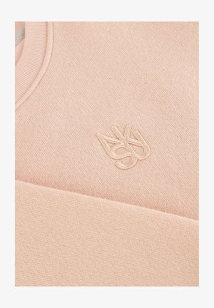 Zacht roze breiwerk met subtiele geborduurde logo's met in elkaar vervlochten letters "A" en "S" nabij de halslijn.