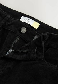 Pantaloni negri slim-fit cu un design cu talie medie. Au fermoar, închidere cu buton metalic și o textură moale similară suedeului. Etichete vizibile în interior.