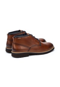 Botas chukka de cuero marrón con un acabado suave, costuras en contraste, punta redondeada y un cuello acolchado para mayor comodidad.