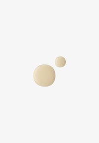 Deux gouttes de liquide beige de tailles différentes sur un fond blanc uni, la goutte la plus grande en dessous et à gauche de la plus petite.