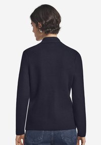 Granatowy sweter z teksturowanym splotem, z kołnierzem, długimi rękawami i prostym krojem, w zestawieniu z niebieskimi dżinsami, prezentujący widok z tyłu.