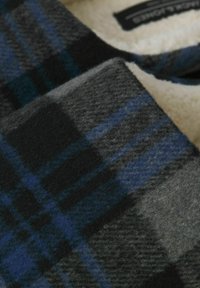 Tissu en laine à carreaux avec des nuances de gris, noir et bleu, doté d'une surface douce et texturée et d'une doublure en polaire pour plus de chaleur.