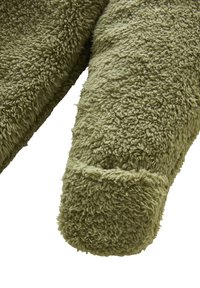 Olivengrüner, flauschiger Fleece-Arm eines Kleidungsstücks mit einem runden Bündchen. Das Material wirkt weich mit einer strukturierten, strubbeligen Oberfläche.