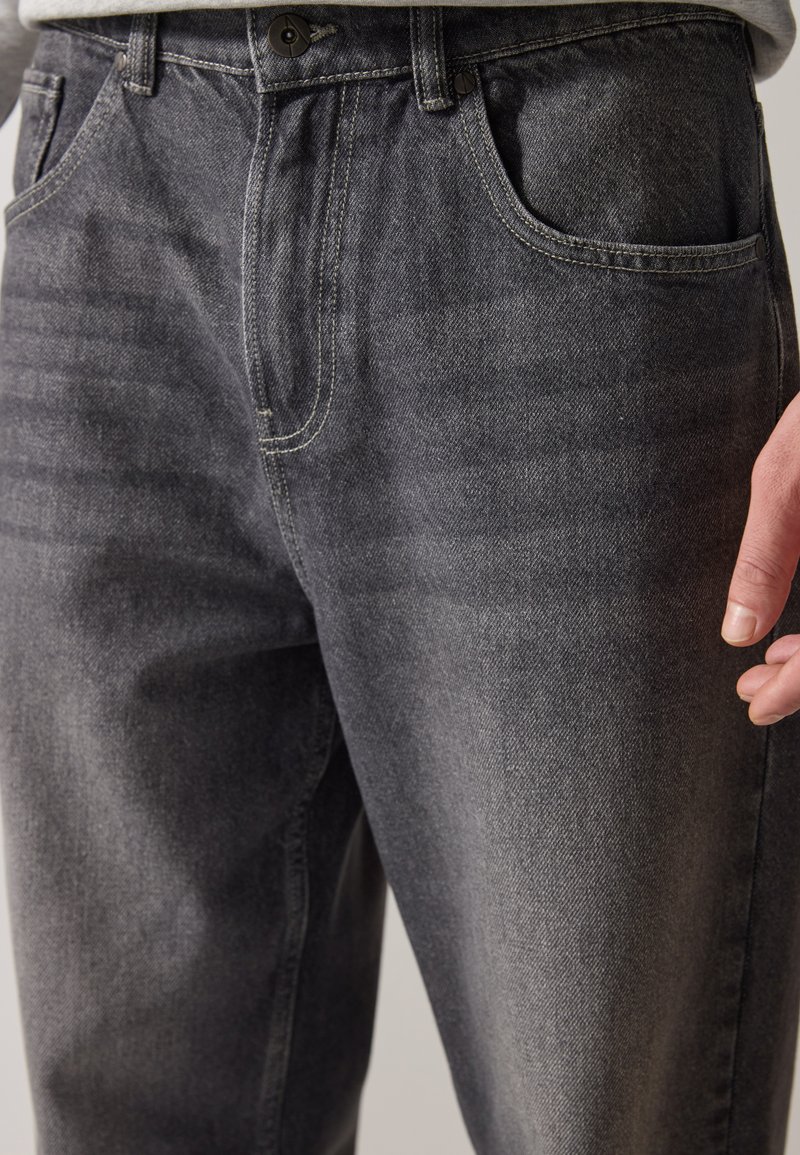 Ciemnoszare dżinsy o prostym kroju, pięć kieszeni oraz kontrastowe detale szwów. Materiał jest teksturowany z gładkim wykończeniem.