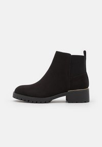 Stivali alla caviglia in suede nero con tacco a blocco, pannelli laterali elasticizzati e un accento dorato sul tacco. Suola robusta per una migliore aderenza.