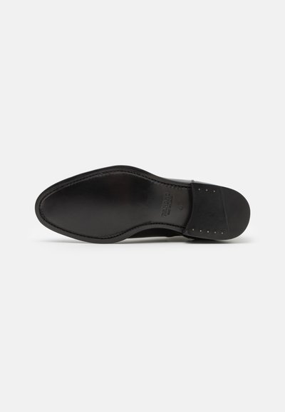 Suela de zapato de vestir de cuero negro con costuras visibles, marcada "Sandro", tamaño 43, mostrando las áreas del dedo del pie y el talón con clavos metálicos en el talón.