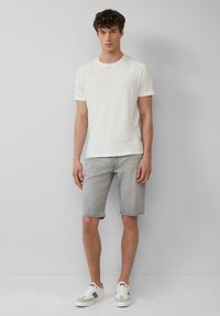 T-shirt en coton blanc, shorts en denim gris, et baskets crème. Coupe ajustée, manches courtes, design décontracté sans motifs ni logos visibles.