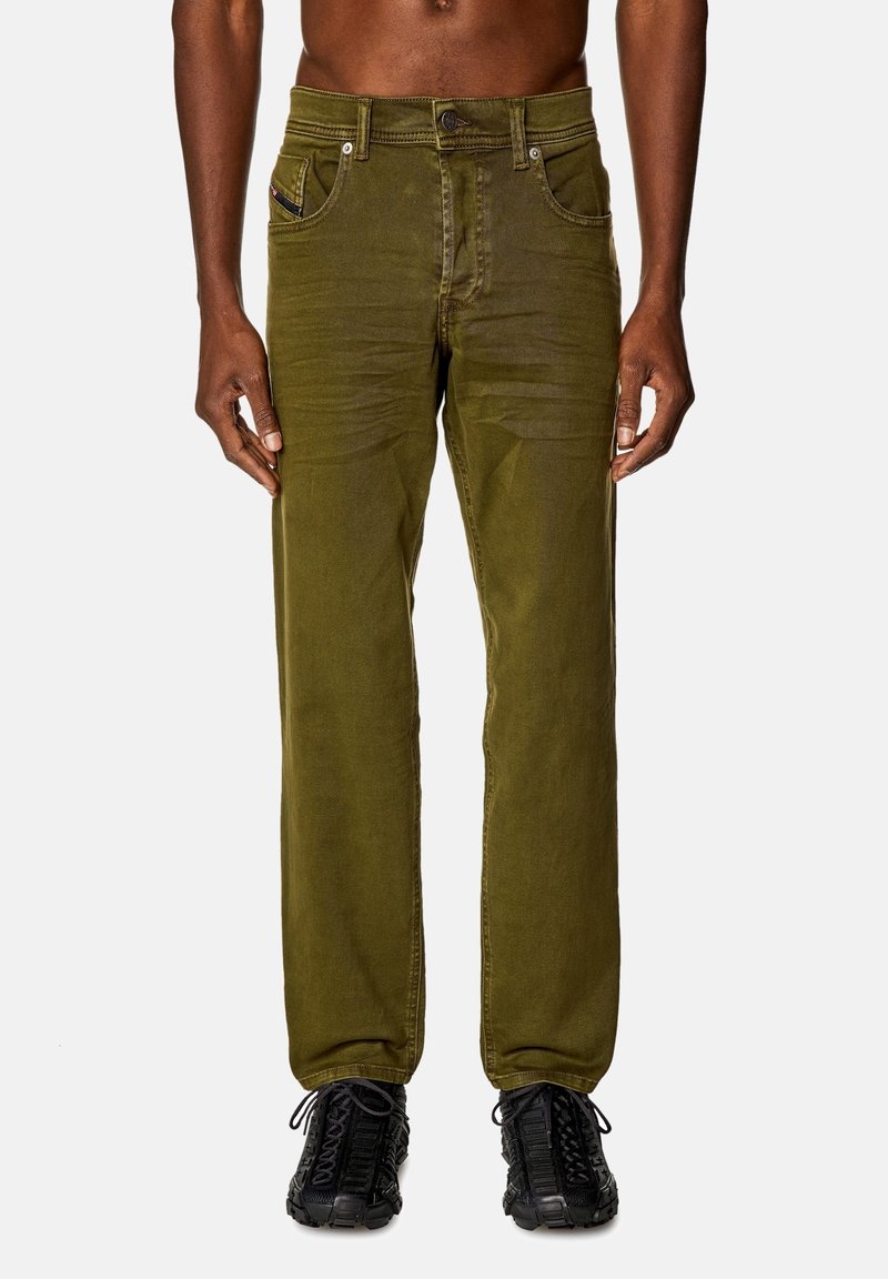 Pantaloni in denim di cotone verde oliva con gambe dritte, cinque tasche e chiusura con bottone in metallo. Indossati con sneakers nere testurizzate.