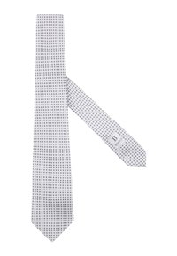 Cravate blanche avec un motif circulaire sombre bleu navy répétitif, en tissu lisse. Présente une étiquette de marque grise avec des lettres foncées.