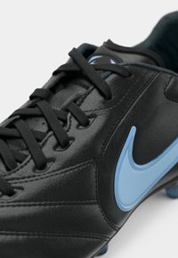 Μαύρο ποδοσφαιρικό παπούτσι από δέρμα με μαύρα κορδόνια και ανοιχτό μπλε λογότυπο Nike Swoosh στο πλάι, απεικονισμένο σε κοντινό πλάνο.