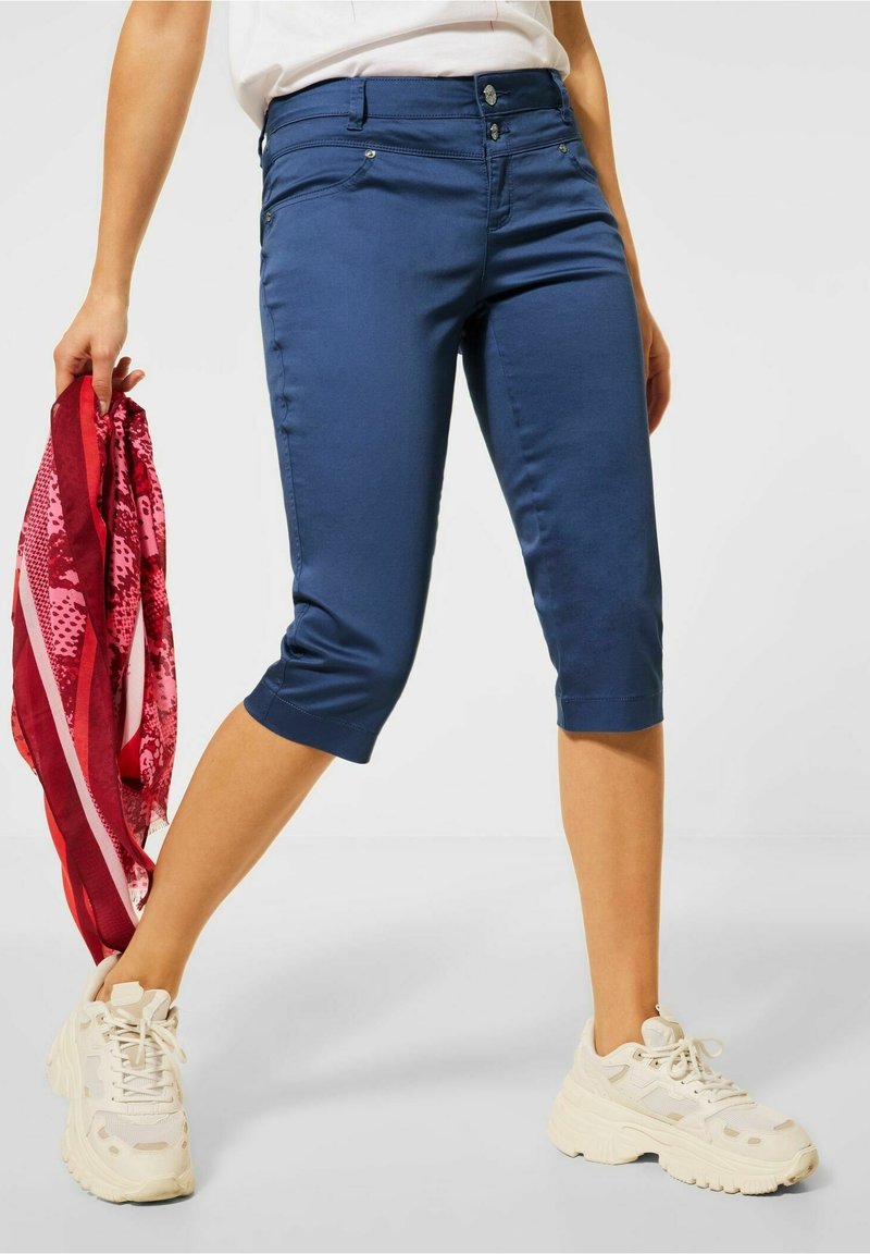 Námořnické modré capri kalhoty vyrobené z elastického materiálu, s přiléhavým střihem, středně vysokým pasem, předními kapsami a ohrnutým lemem.