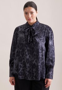 Schwarz-graue Leopardenmusterbluse mit einer Schleifenkragen, langen Ärmeln und gerafften Schultern, die eine glatte, satinähnliche Textur aufweist.