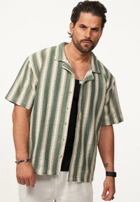 Kurzärmeliges Hemd mit grün- und cremefarbenen Streifen, Knopfleiste vorne, aus strukturiertem Stoff, mit Kragen.