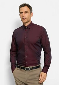 Maroonfarbenes Langarmhemd aus glattem Stoff, mit Standardkragen und durchgehender Knopfleiste. Das Hemd hat eine taillierte Passform.