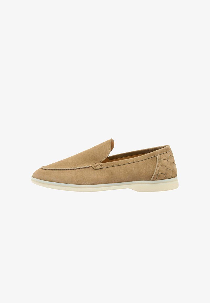Mocassin beige en daim à enfiler avec semelle blanche et détail tissé sur le talon, conçu pour un port décontracté ou semi-formel.