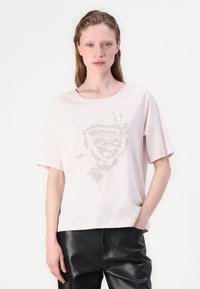 Rosa bomull T-skjorte med korte ermer, med et subtilt, teksturert grafisk design i midten. Kombinert med svarte lærbukser.