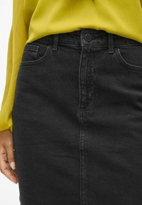 Črna denim krilo s ravnim krojem, ki vključuje sprednje žepke, zaklep na kovinsko gumb in rahlo teksturirano površino.