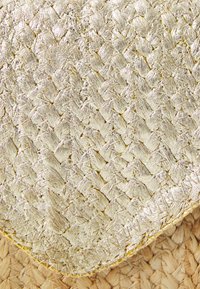Gullvevet jute matte med en teksturert overflate. Har et kryssmønster og avrundede kanter, som fremhever metallglansen til materialet.