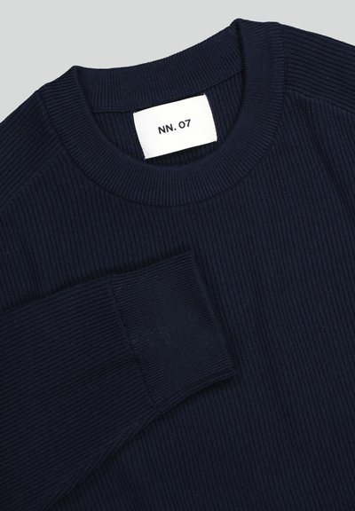 Marineblå ribstrikket sweater med rund halsudskæring og lange ærmer, med en hvid label ved kraven, hvor der står "NN. 07".