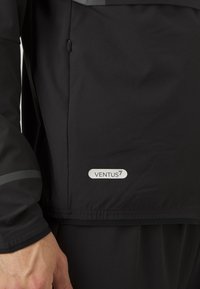 Μαύρο αδιάβροχο μπουφάν με μάτ υφή, διαθέτει τσέπη με φερμουάρ και ανακλαστικές γκρίζες λεπτομέρειες. Λογότυπο "VENTUS" στο κάτω φάσμα.