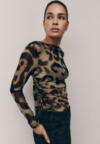 Maglia a maniche lunghe in tessuto semi-trasparente con un motivo a stampa leopardata in tonalità di marrone e nero, caratterizzata da arricciature laterali e una silhouette aderente.