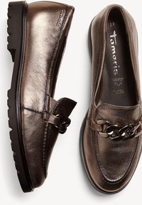 Mocassins en cuir métallisé marron avec un détail de grosse chaîne noire et semelles en caoutchouc noir, taille 37, marque "tamaris" visible à l'intérieur.