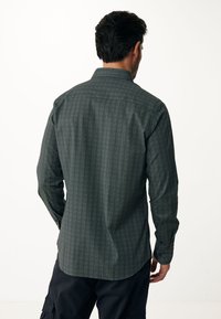 Camicia da uomo a maniche lunghe di colore verde scuro con motivo a spina di pesce, dotata di colletto classico e polsini con bottone, realizzata in tessuto testurizzato.