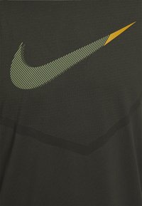Camiseta deportiva negra con un prominente logo de Nike en verde y amarillo, con detalles a rayas, hecha de una tela texturizada.