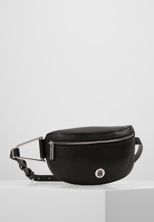 Black leather belt bag with silver zipper and logo detail, adjustable strap with metal buckle, displayed on white pedestal against plain background.
