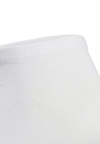 Calcetín de algodón blanco de punto con un puño acanalado, textura suave y diseño de punta sin costuras. Sin patrones visibles ni detalles de hardware.