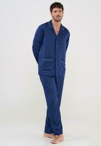 Conjunto de pijama de patrón cuadrado en color marino, hecho de tela suave, que incluye una camisa de botones con detalles en blanco y dos bolsillos, acompañada de pantalones a juego.