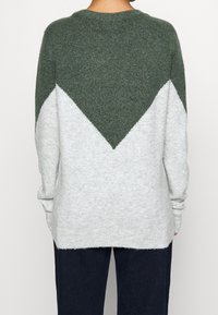 Maglione lavorato a maglia verde e grigio chiaro con motivo a zigzag, dotato di un collo rotondo e vestibilità morbida, tessuto testurizzato e polsini a coste.