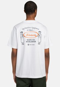 Hvid bomulds t-shirt med et grafisk print på ryggen, som inkluderer tekst, illustrationer af figurer og en orange accent rundt om ordet "Element."
