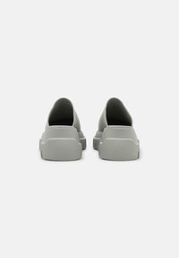 Instappers in lichtgrijs, met een zachte bovenkant, ronde neus en een gestructureerde rubberen zool met een lage, dikke hak.