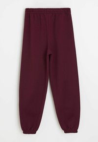 Bordowe dresy wykonane z miękkiego materiału, z elastycznym pasem i zwężanymi mankietami, o gładkiej fakturze i bez widocznych wzorów.