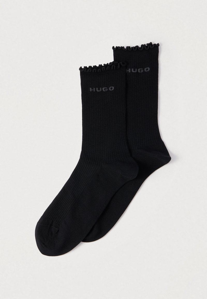 Čierne rebrované ponožky s volánikovým lemom navrchu, na boku s šedým logom "HUGO". Vyrobené z mäkkej látky pre pohodlie a odolnosť.