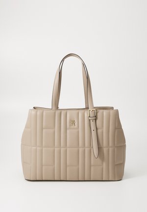 Beige Leder-Tote mit gestepptem Muster, ausgestattet mit zwei Schulterriemen und einem goldenen Logo-Detail auf der Vorderseite. Saubere Linien und strukturierte Form.