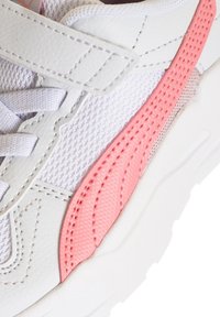 Scarpa da ginnastica bianca con parte superiore in rete e accenti rosa, sovrapposizioni sintetiche testurizzate e una fascia con chiusura a velcro.